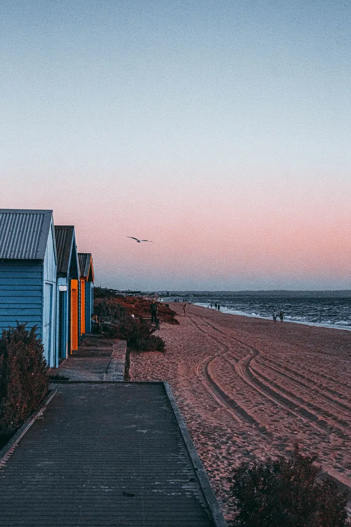 Melbourne's colourful bathing boxes along the sand at sunset