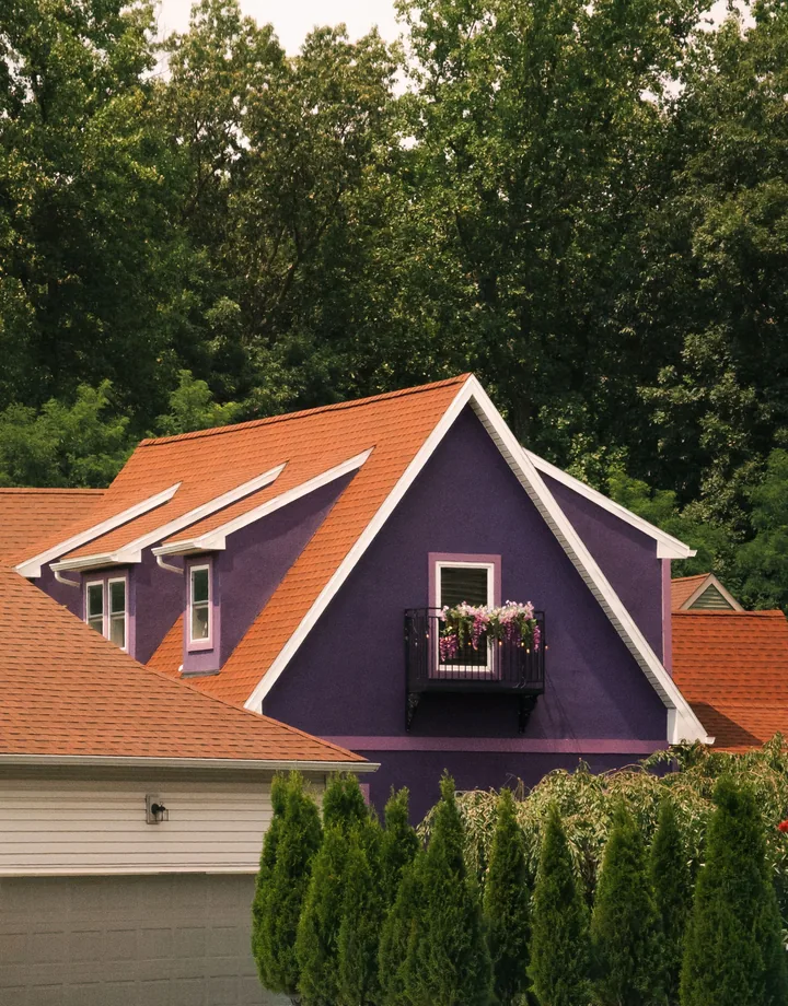 A plum-violet home with a terracotta roof in summer sun
